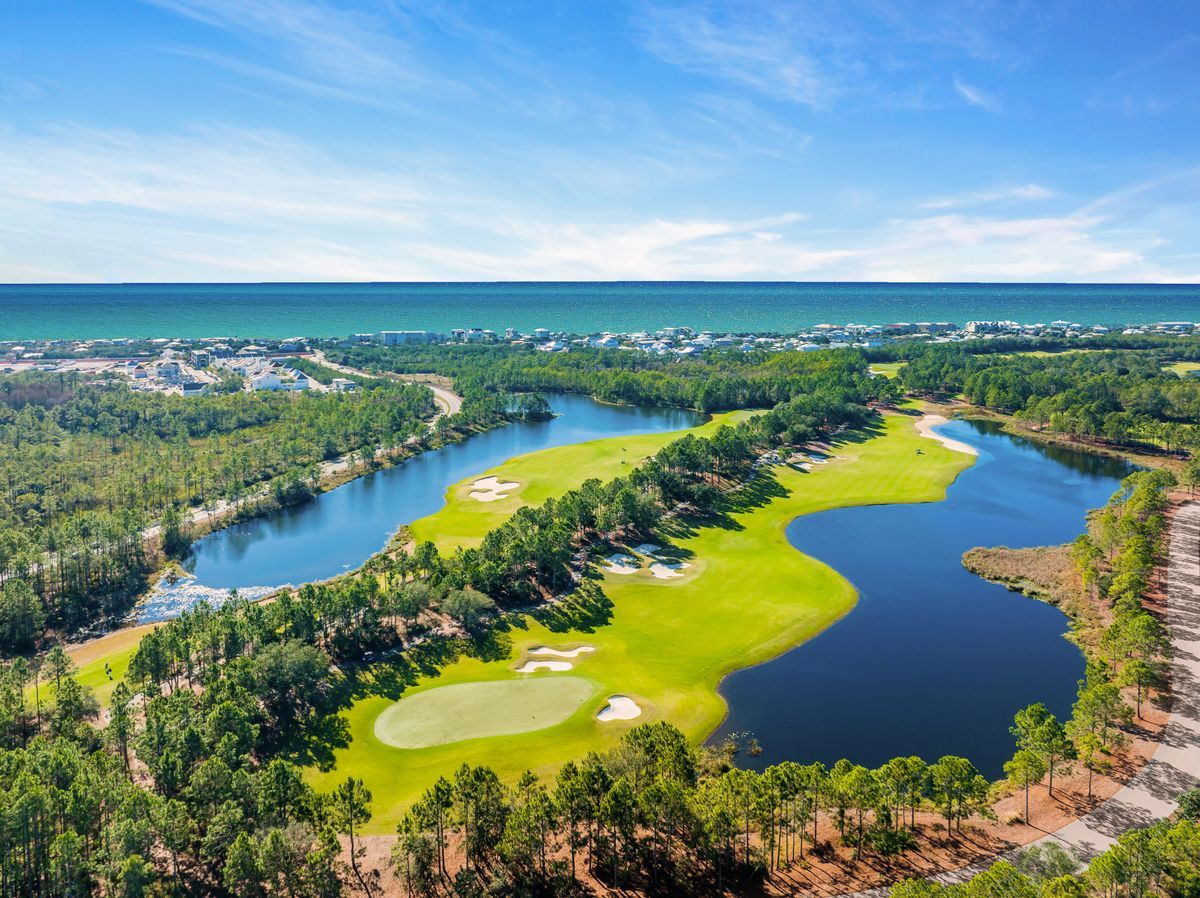 An aerial view of the golf coarse at Watersound Camp Creek with the Gulf in the background on a sunny day.